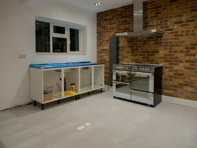 A kitchen with a stove and a brick wall